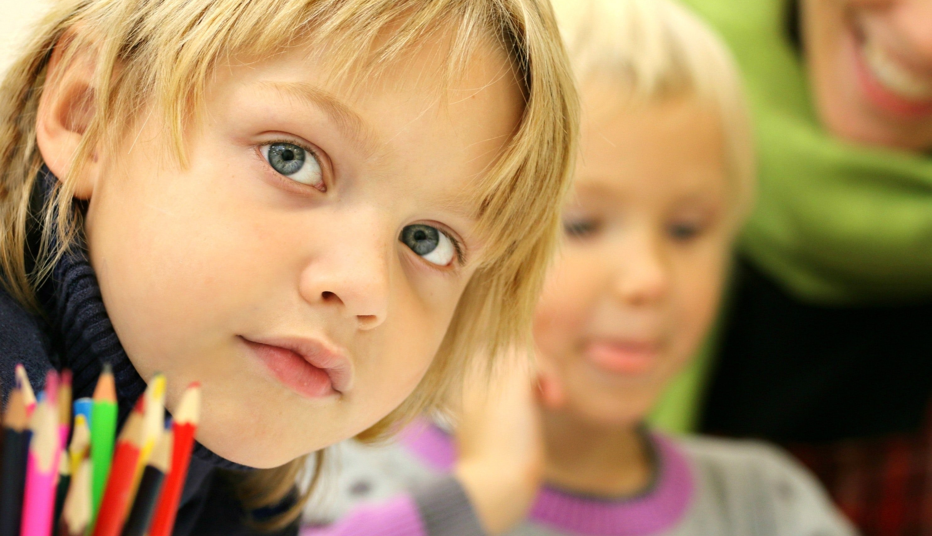 Ett barn i förgrund, ett barn och en vuxen i bakgrund